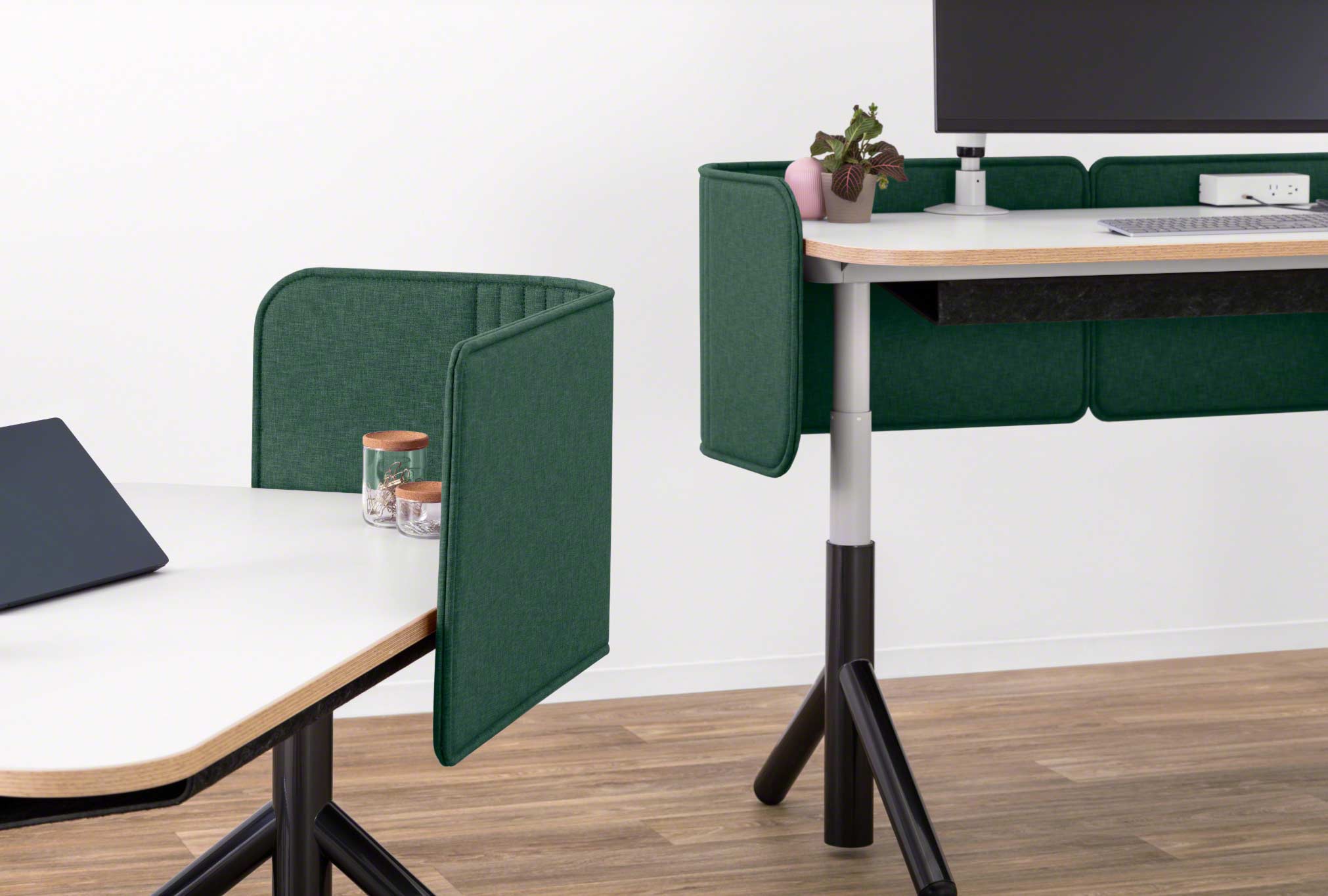 Close-up of Two Steelcase Flex height-adjustable desks pictured with green privacy screens attached.